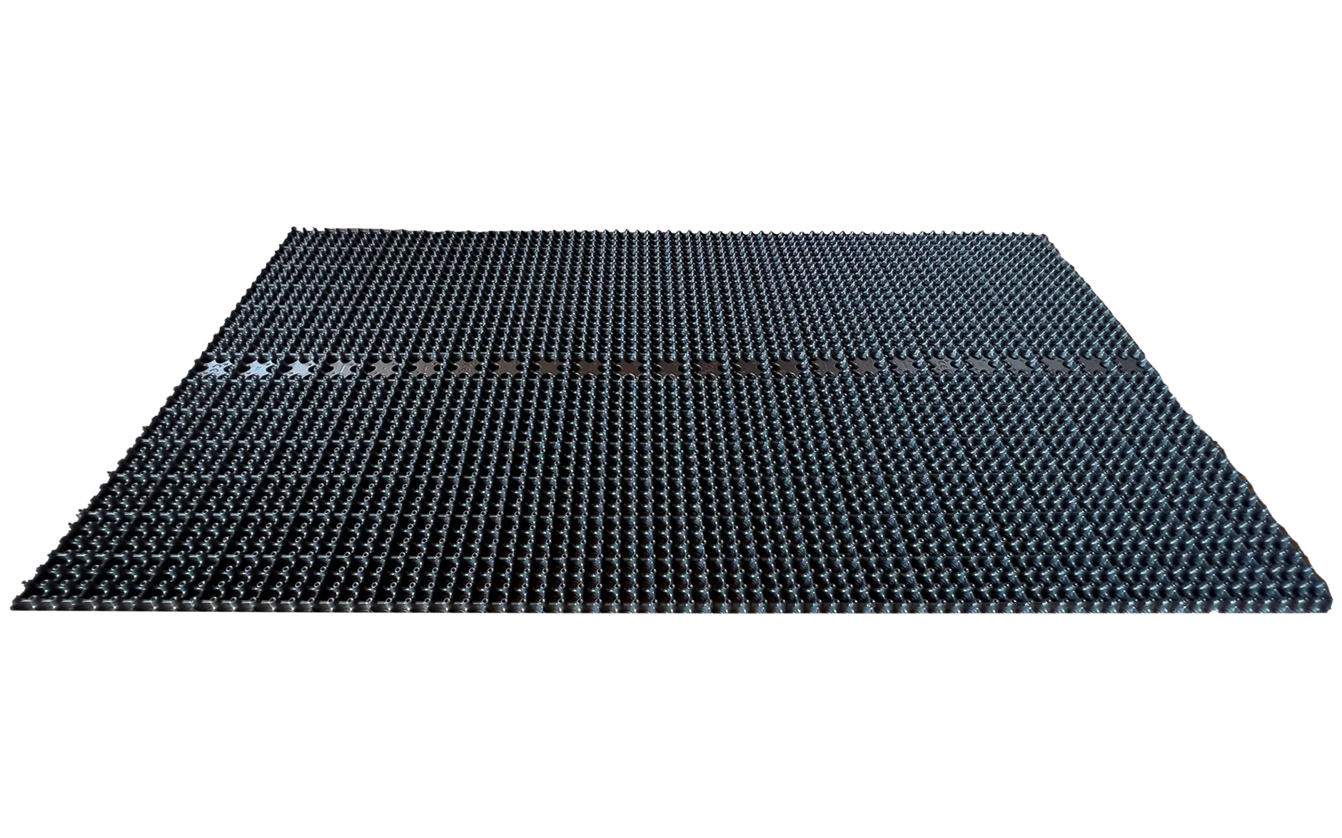 Isolert dreneringselement på mørk bakgrunn: rektangulær, svart drensplate med tett mønster av små nupper/knotter og en tydelig skjøt/klikk-kant på midten, sett i lav vinkel.