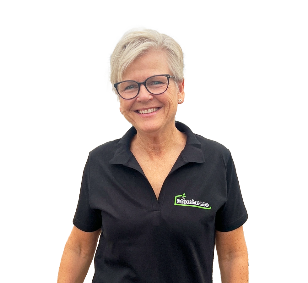 Isolert portrett av Aud Toril Trandem på gjennomsiktig bakgrunn: smilende kvinne med kort, grått hår og briller, iført svart polo med utomhus.no-logo.