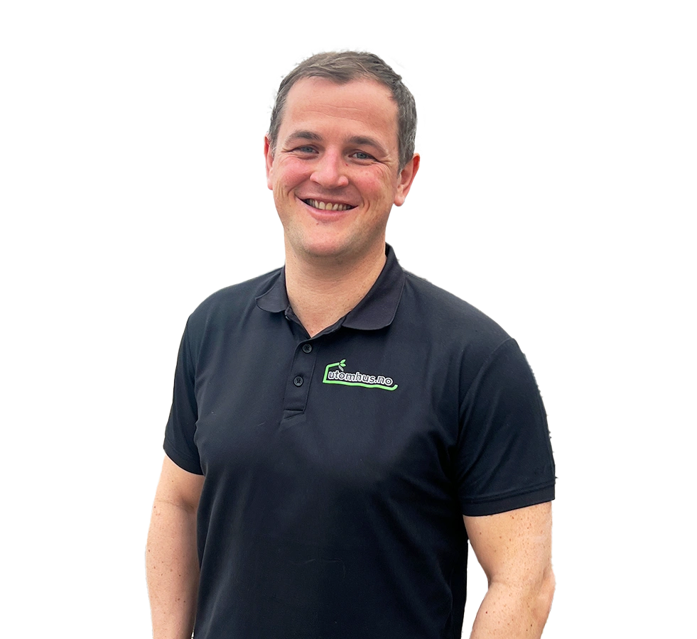 Isolert portrett av Ole Christian Trandem på gjennomsiktig bakgrunn: smilende mann med kort, mørkt hår, iført svart polo med utomhus.no-logo, stående lett på skrå mot kamera.