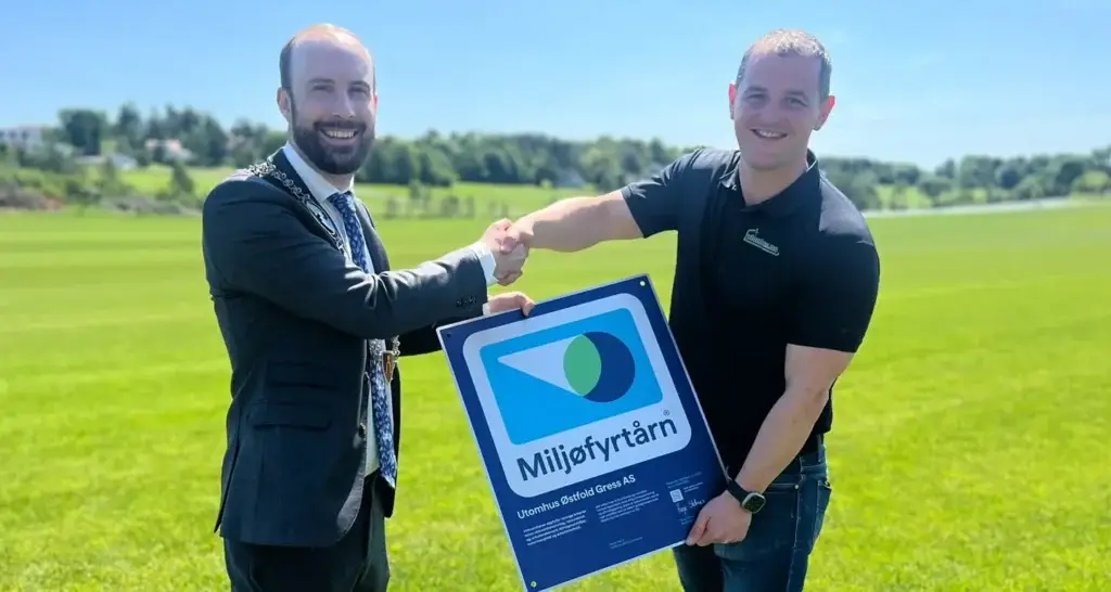 Simen Nord, ordfører av Moss Kommune, overrekker miljøsertifisering til Ole Christian Trandem på en stor gressplen
