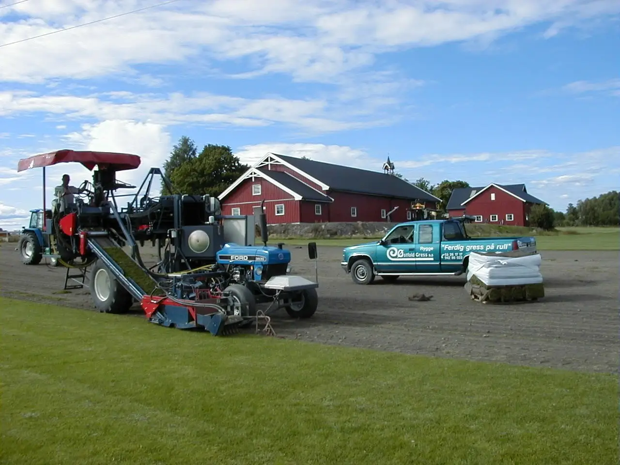 Arkivfoto av første gresskjærer og utstyr for produksjon av ferdigplen på gårdsområde.