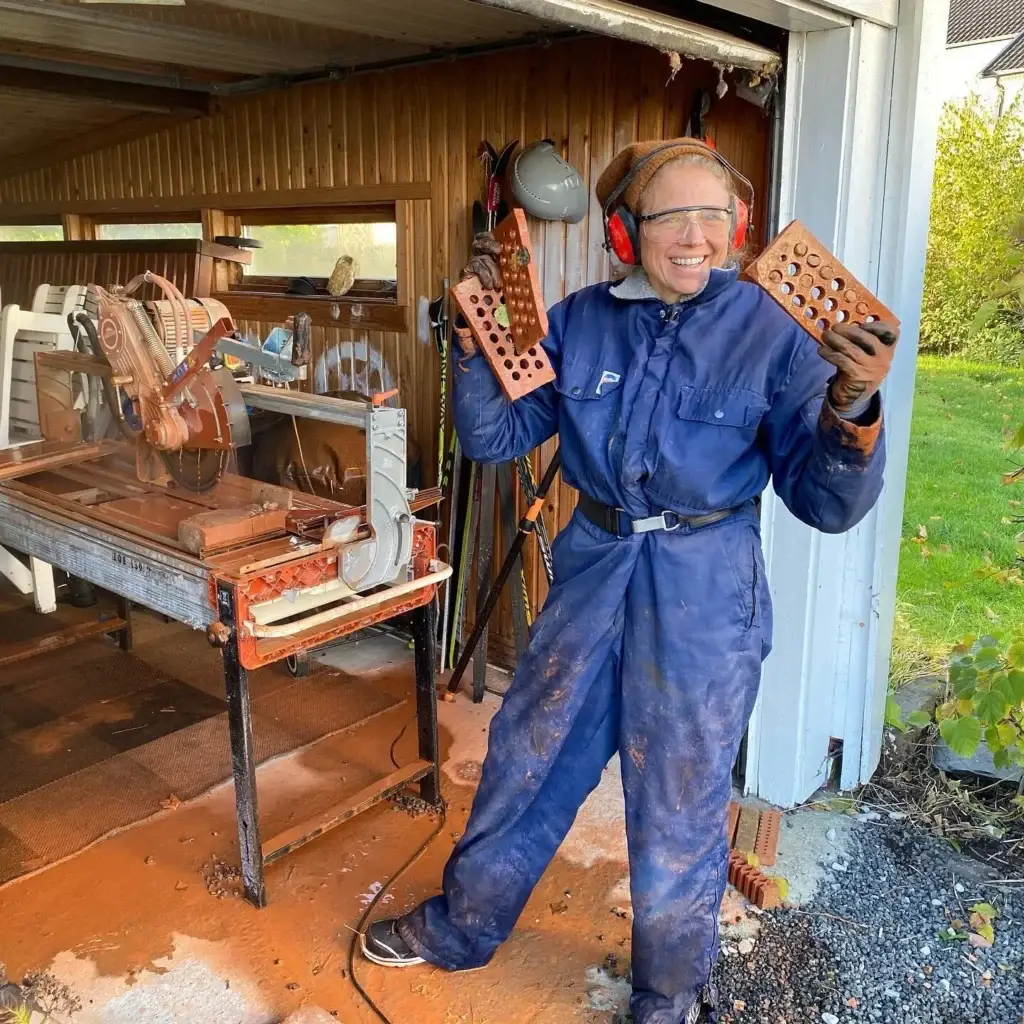 Jorunn Tyssø fra Høine, med verneutstyr og to teglsteiner i hendene
